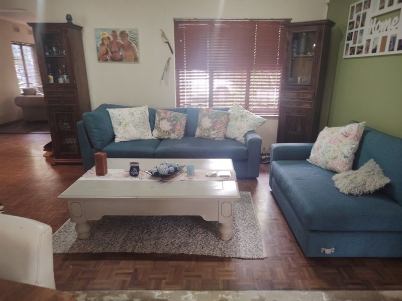 A comfortable living room featuring classic parquet flooring and venetian blinds, providing a warm and functional space for relaxation.