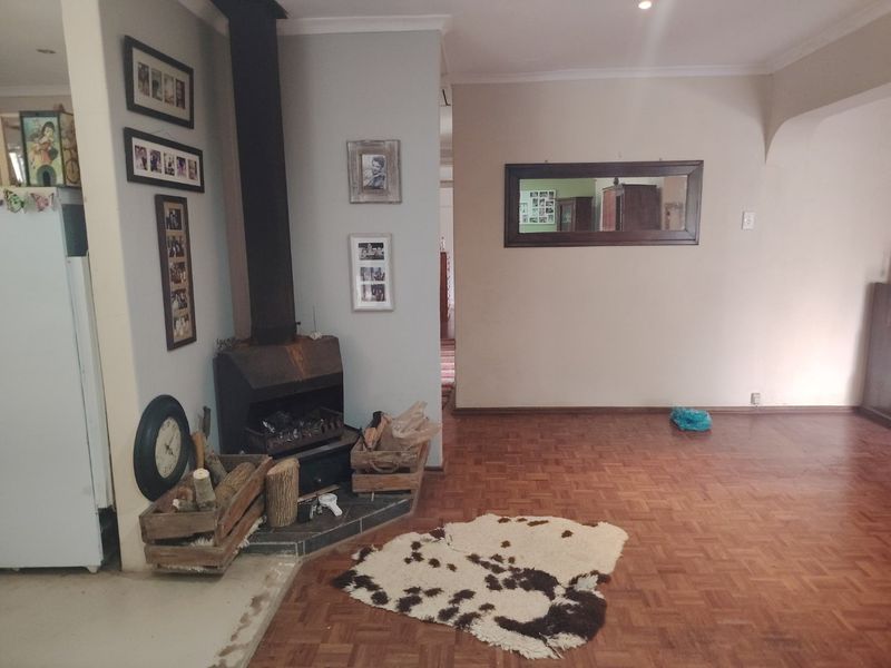 Living room featuring a corner freestanding fireplace and traditional parquet flooring, offering a cozy atmosphere with potential for cosmetic updates.