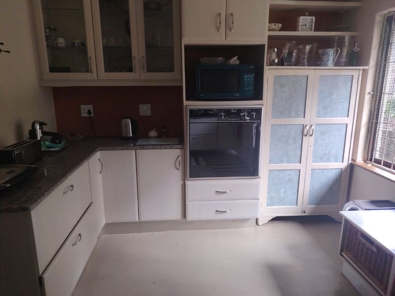 A functional kitchen featuring built-in oven and microwave, granite countertops, and ample cabinetry, offering a practical layout with potential for modern cosmetic updates.