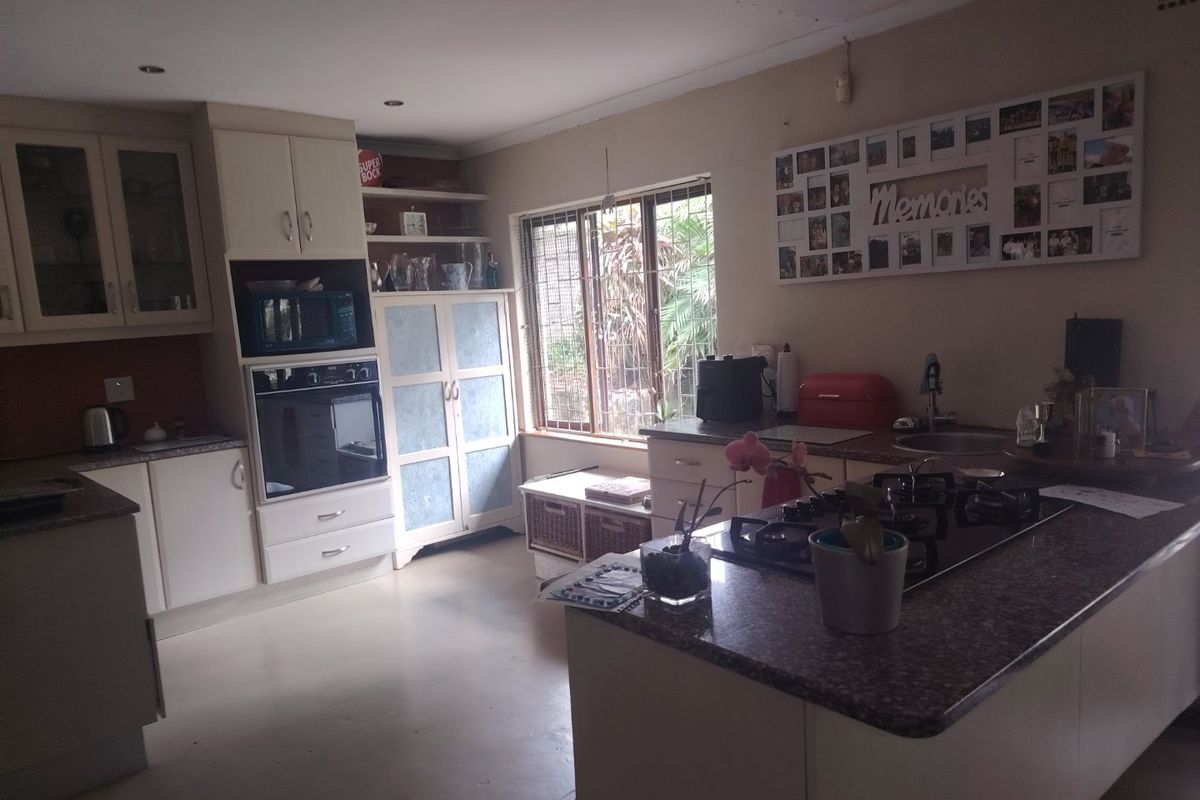 Functional kitchen featuring built-in cabinetry, granite countertops, integrated oven, gas cooktop, and recessed lighting, with a window overlooking the garden area.