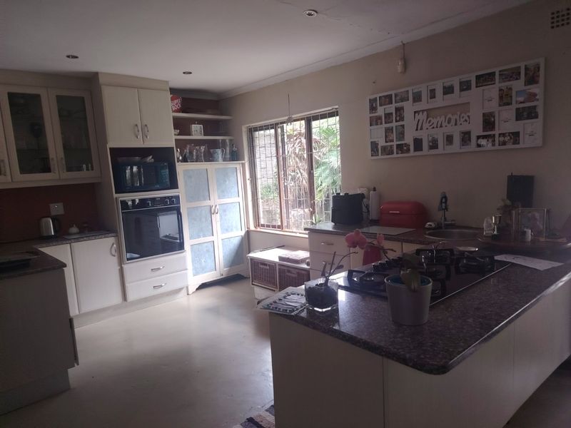 Functional kitchen featuring built-in cabinetry, granite countertops, integrated oven, gas cooktop, and recessed lighting, with a window overlooking the garden area.