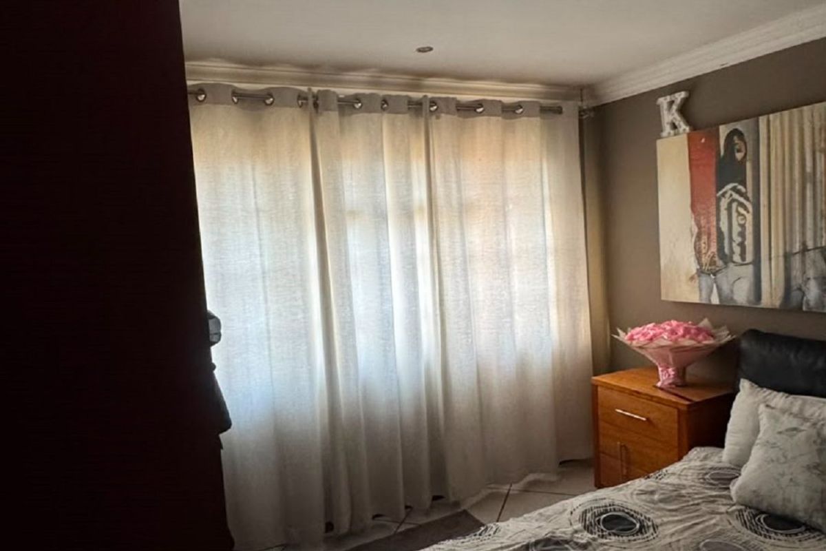 A bedroom featuring tiled flooring, recessed downlighting, and decorative cornicing, providing a functional space with natural light through the window.