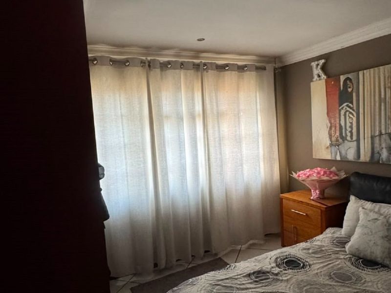 A bedroom featuring tiled flooring, recessed downlighting, and decorative cornicing, providing a functional space with natural light through the window.