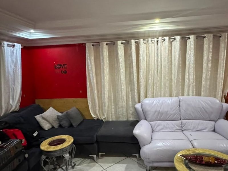 A living room featuring tiled flooring, coved ceiling details, and recessed lighting, providing a functional space for relaxation.