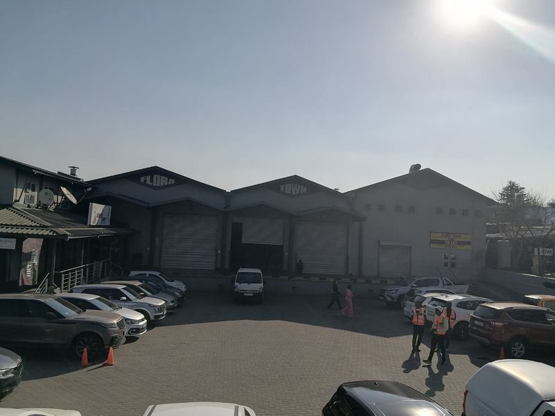 Front view of a commercial warehouse complex featuring multiple roller shutter doors, loading bays, and a paved parking area.