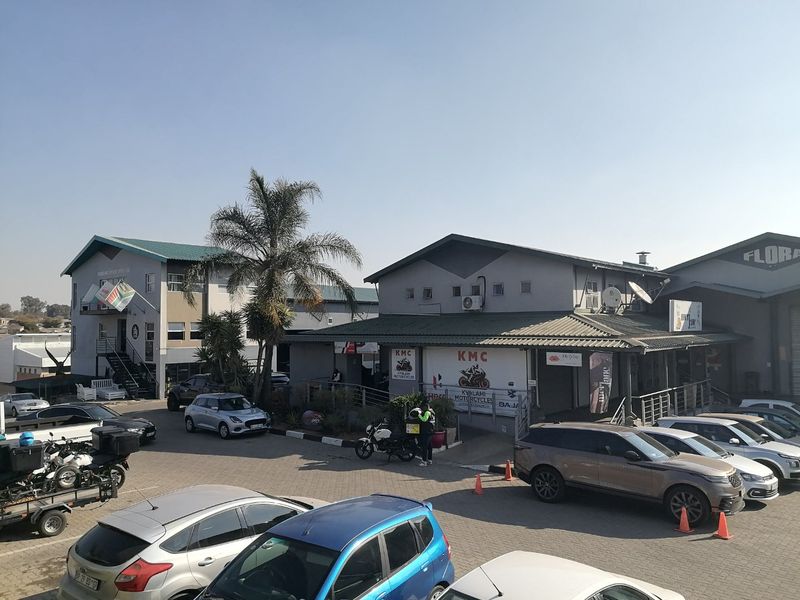 Exterior view of a commercial property complex featuring paved parking, multiple building facades, and external access points.