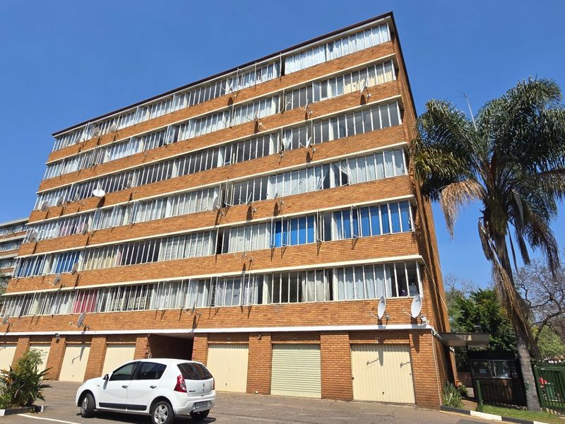 A multi-story brick apartment building featuring ground-level garage access and large windows across multiple residential levels.