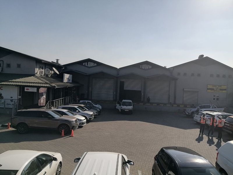 Front exterior view of a commercial warehouse complex featuring multiple roller shutter doors, a loading bay, and a paved parking area.