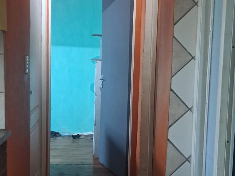 A narrow interior hallway featuring tiled flooring and multiple doorways leading to adjacent rooms, requiring cosmetic updates to the wall finishes.