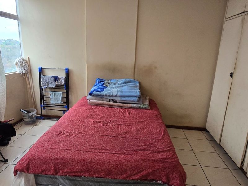 A bedroom featuring tiled flooring and a built-in wardrobe, requiring cosmetic updates to the wall finishes.