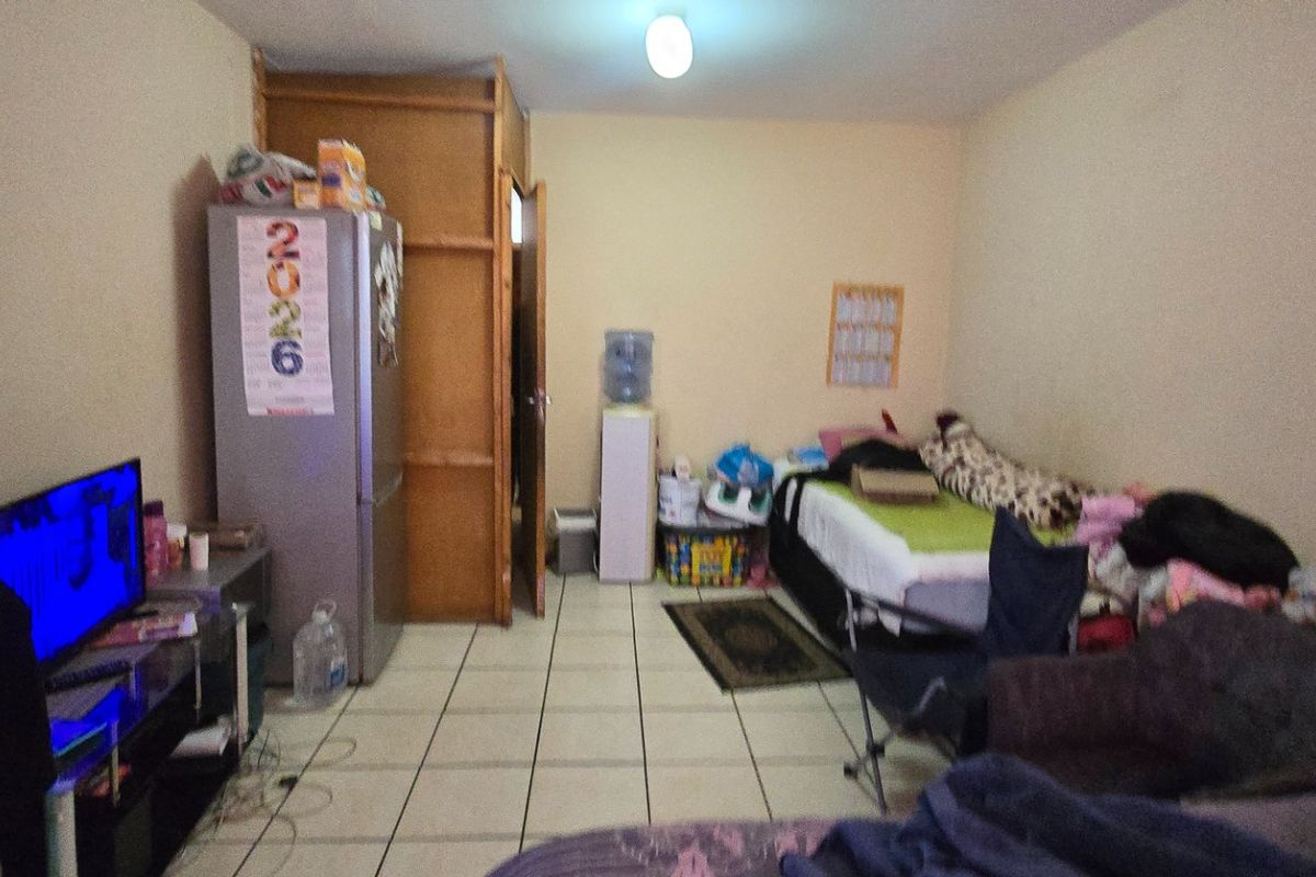 A bedroom featuring tiled flooring and a built-in cupboard, offering a functional space that could benefit from cosmetic updates.