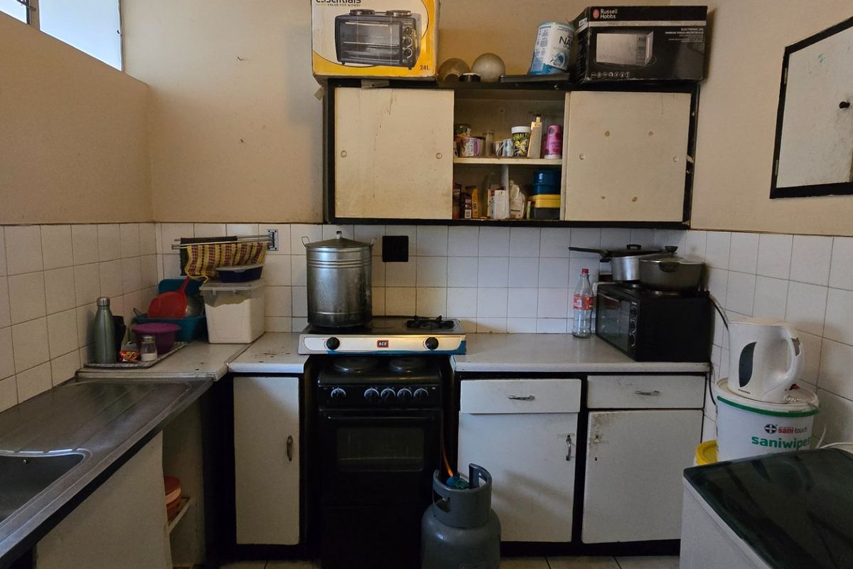 A functional kitchen featuring a stainless steel sink, tiled splashback, and built-in cabinetry with an integrated gas stove and oven.