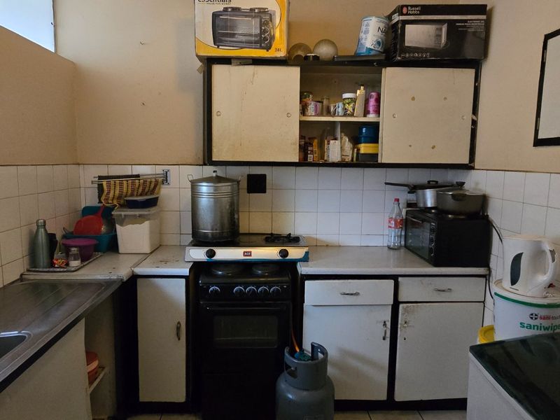 A functional kitchen featuring a stainless steel sink, tiled splashback, and built-in cabinetry with an integrated gas stove and oven.