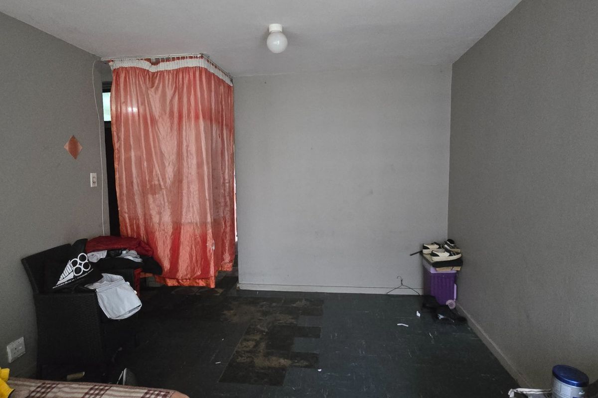 A bedroom space featuring grey walls and dark flooring, requiring cosmetic updates and repairs to improve the overall condition and appeal.