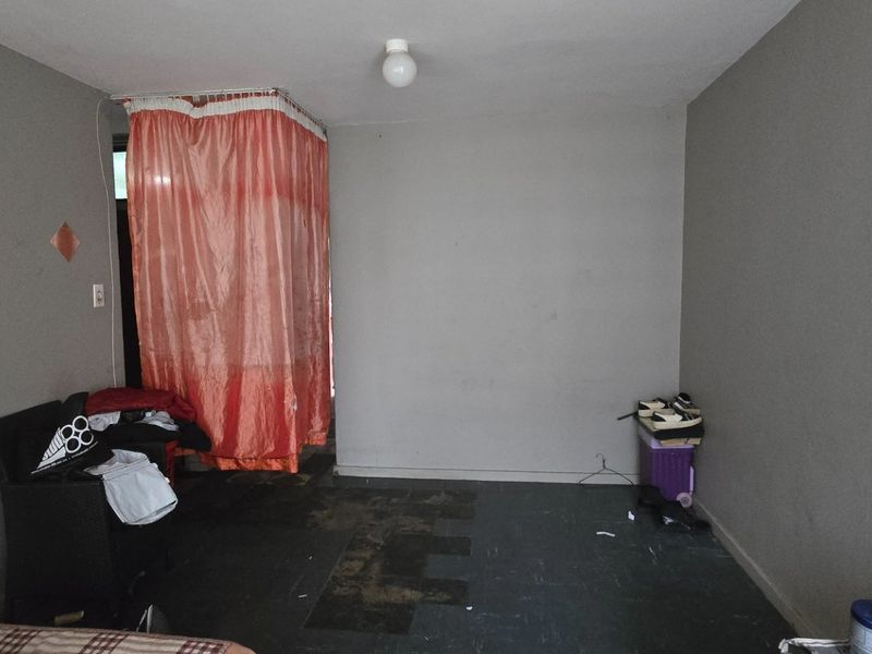 A bedroom space featuring grey walls and dark flooring, requiring cosmetic updates and repairs to improve the overall condition and appeal.