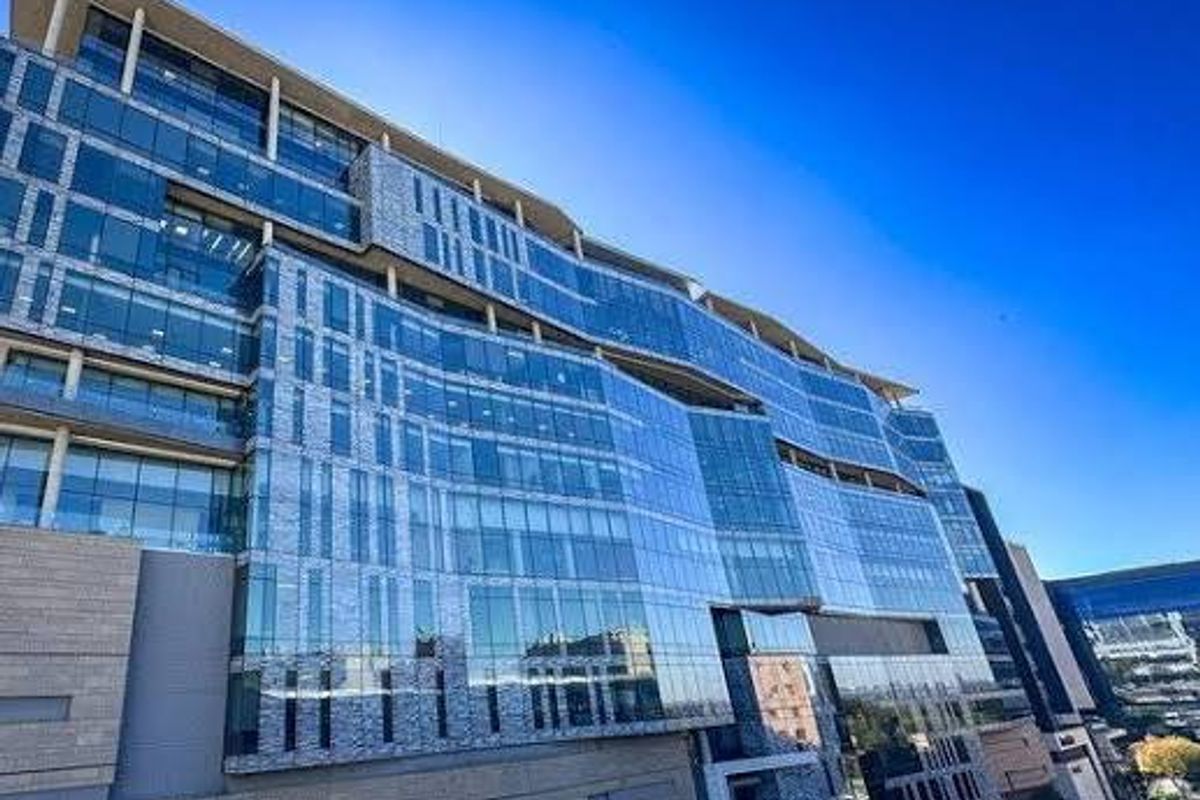 A modern multi-story commercial office building featuring an extensive glass curtain wall facade and stone cladding elements.
