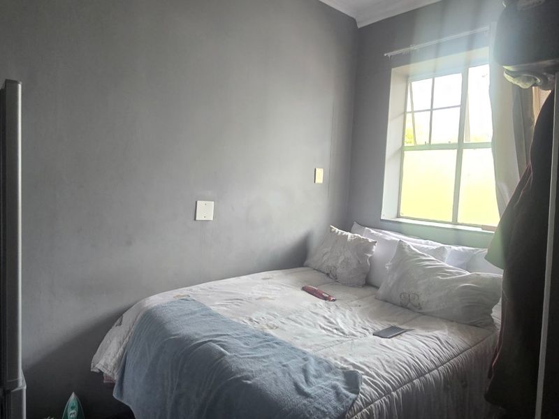 A compact bedroom featuring a casement window and neutral wall finishes, providing a functional sleeping space.