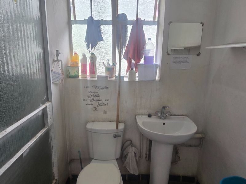 A compact bathroom featuring a pedestal basin and toilet, requiring cosmetic updates and maintenance to improve the overall condition of the space.