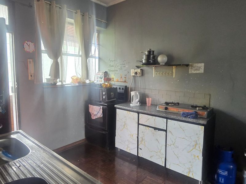 A functional kitchen area featuring a stainless steel sink, gas hob, and built-in cabinetry with a tiled backsplash.
