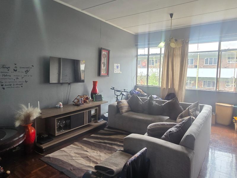A living room featuring parquet flooring and large windows that provide natural light, offering a functional space ready for updates.