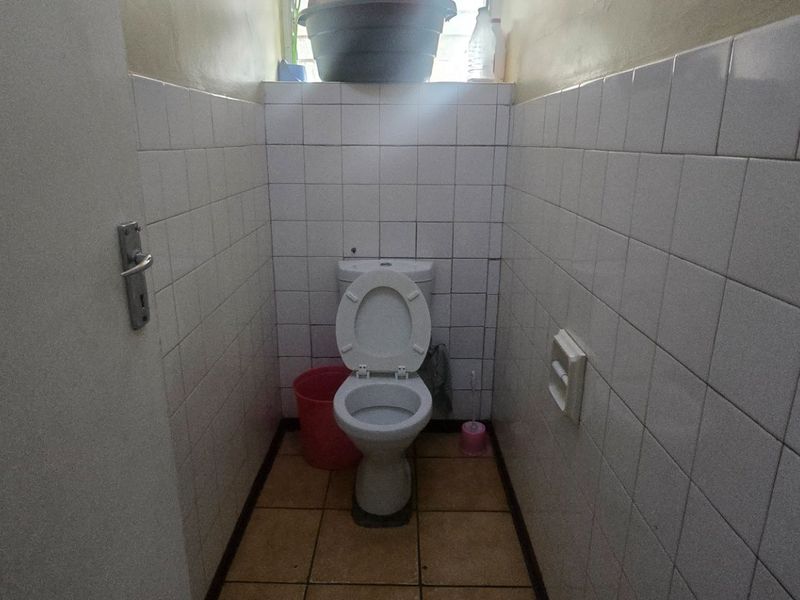 A compact, functional bathroom featuring a standard toilet, tiled walls, and tiled flooring, requiring cosmetic updates to improve its overall condition.