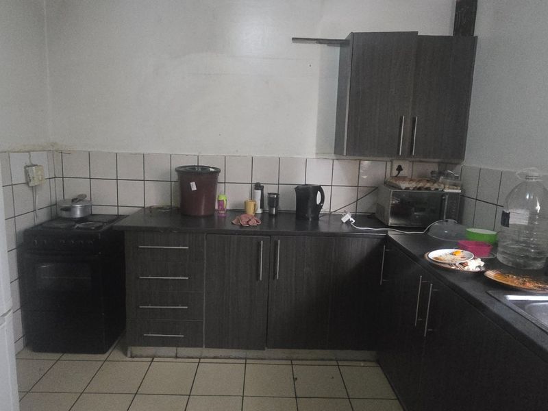 A functional kitchen featuring dark wood-look cabinetry, tiled backsplash, and tiled flooring, offering a practical layout for daily meal preparation.