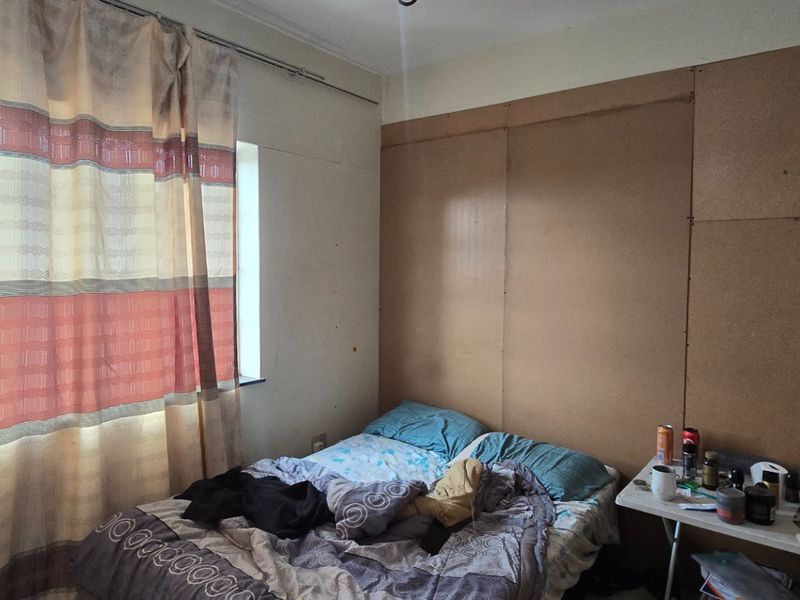A bedroom featuring a window with curtains and unfinished wall paneling, requiring cosmetic updates to improve the overall finish and aesthetic appeal.