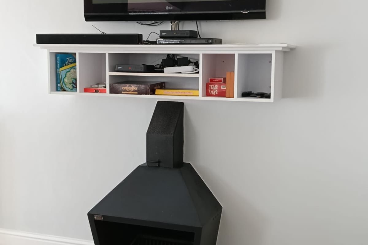 A living area featuring a modern black wall-mounted fireplace and a white floating media shelf with tiled flooring.
