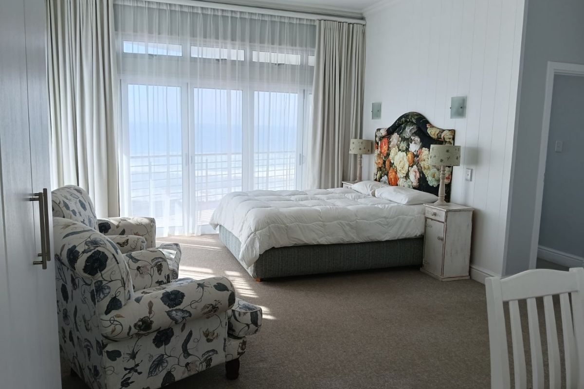 Spacious bedroom featuring wall paneling, carpet flooring, and large sliding glass doors that provide natural light and access to an outdoor area.