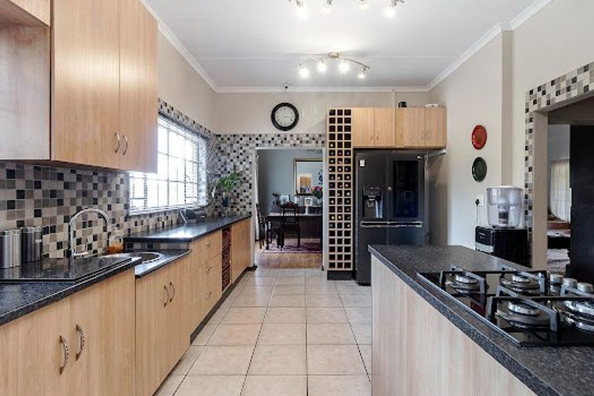 Spacious kitchen featuring light wood cabinetry, dark laminate countertops, mosaic tile backsplash, and a central island with a built-in gas cooktop.
