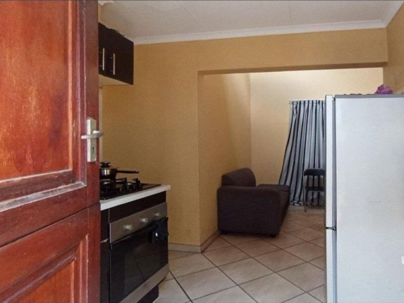 Open plan kitchen and living area featuring tiled flooring, built-in oven, gas hob, and extractor fan.