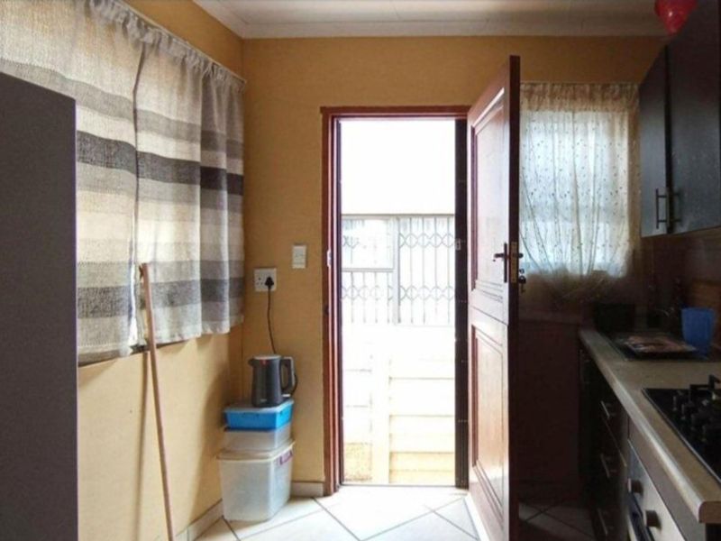 A functional kitchen featuring built-in cabinetry, a gas hob, and an oven, with direct access to an exterior area through a security gate.