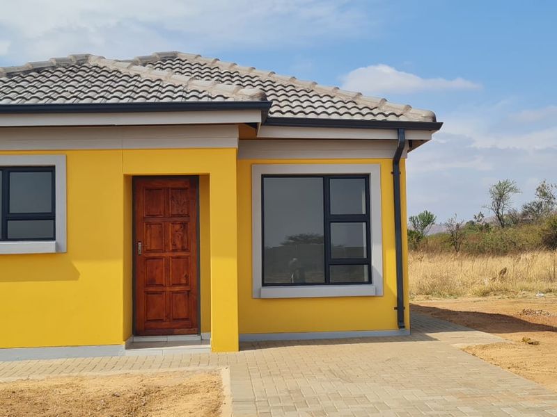 A modern, well-maintained single-story house featuring a vibrant yellow facade, dark tiled roof, and contemporary aluminium window frames.