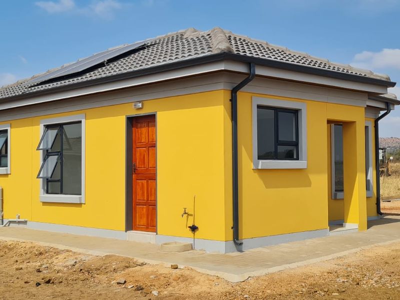 A modern single-story detached house featuring a vibrant yellow facade, tiled roof with solar panels, and aluminium window frames set on a clear plot.