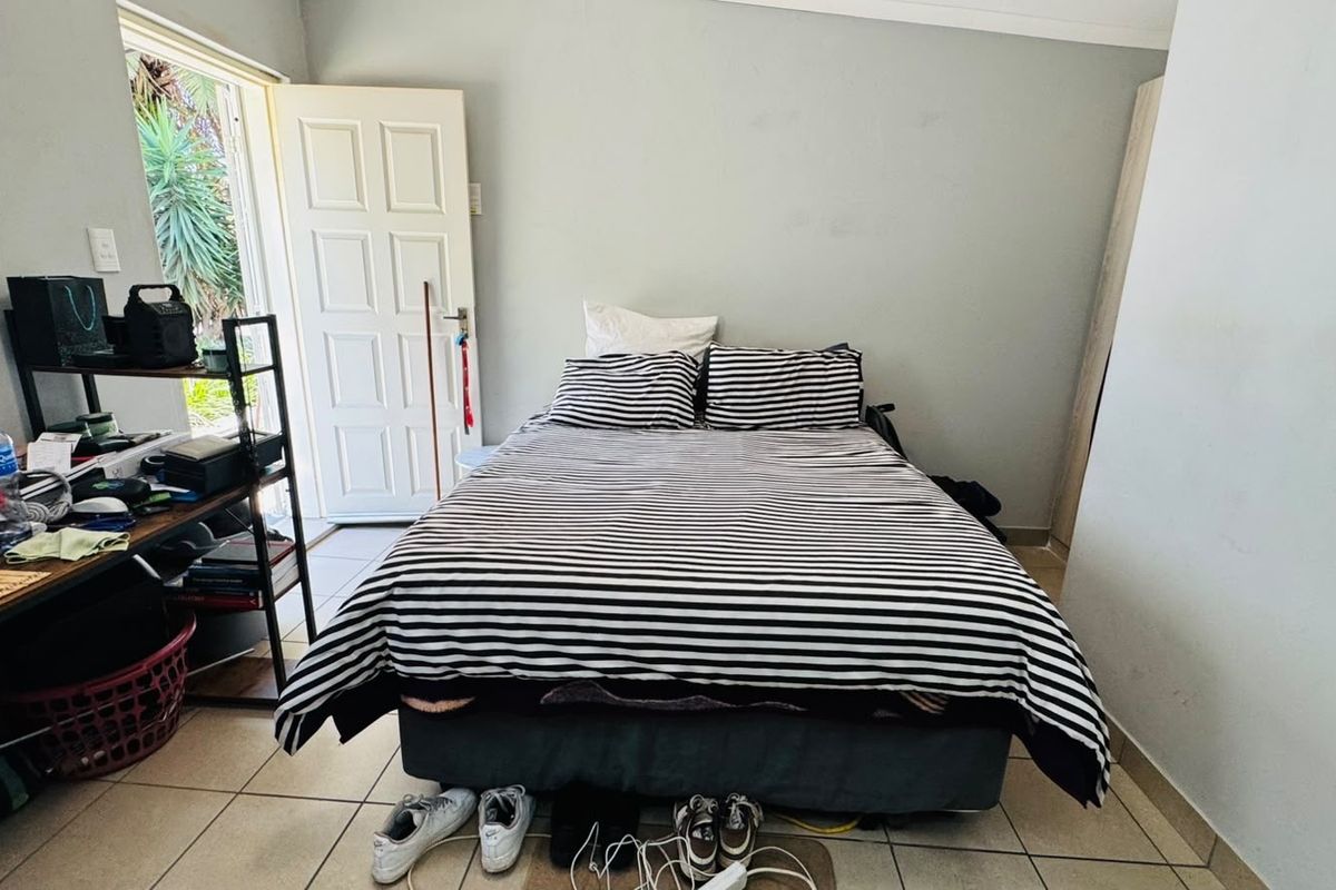 A functional bedroom featuring tiled flooring and direct access to an outdoor area through a panel door.