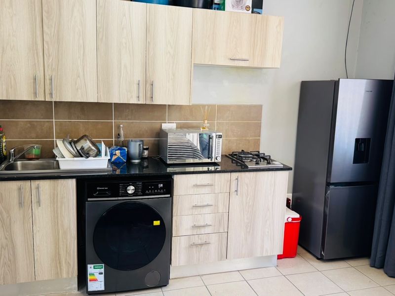 Compact kitchen featuring light wood-grain cabinetry, granite countertops, a gas hob, and tiled backsplash, providing a functional and modern workspace.