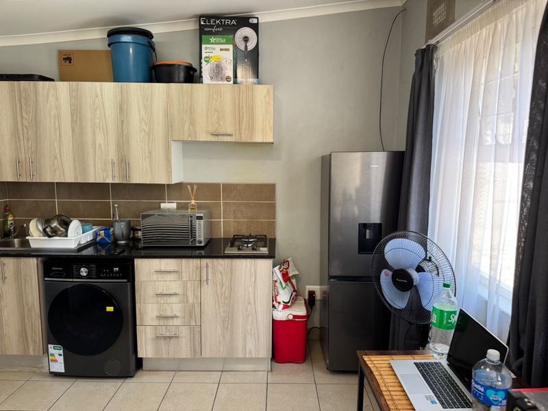 Compact kitchen featuring light wood-look cabinetry, granite countertops, a built-in gas hob, and tiled backsplash, providing a functional workspace.