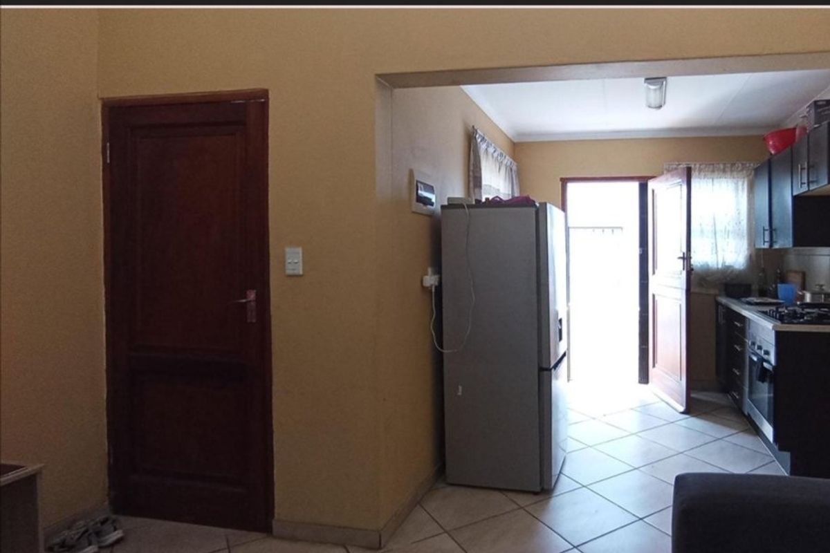A functional kitchen area featuring tiled flooring, built-in cabinetry, and integrated cooking appliances, with direct access to the exterior.