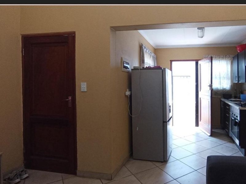 A functional kitchen area featuring tiled flooring, built-in cabinetry, and integrated cooking appliances, with direct access to the exterior.