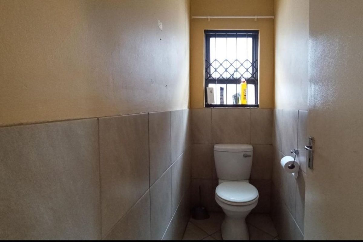 A compact bathroom featuring tiled walls, tiled flooring, and a window with security bars.