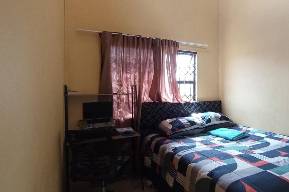 A functional bedroom featuring a window with security bars and neutral wall finishes.