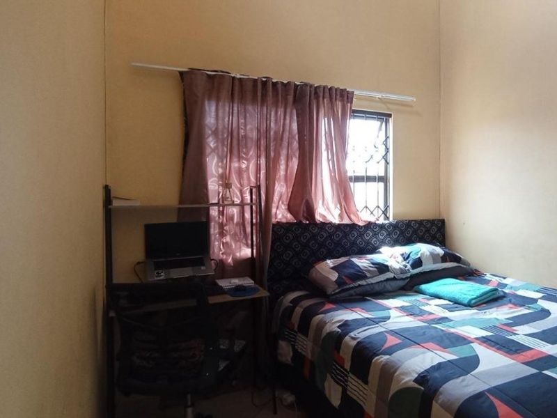 A functional bedroom featuring a window with security bars and neutral wall finishes.