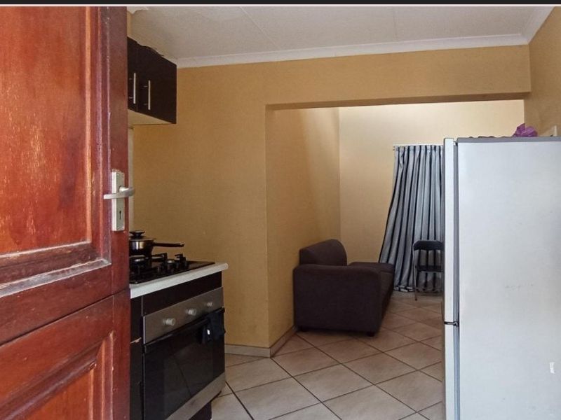 Open plan kitchen and living area featuring tiled flooring, built-in oven, gas hob, and upper cabinetry.