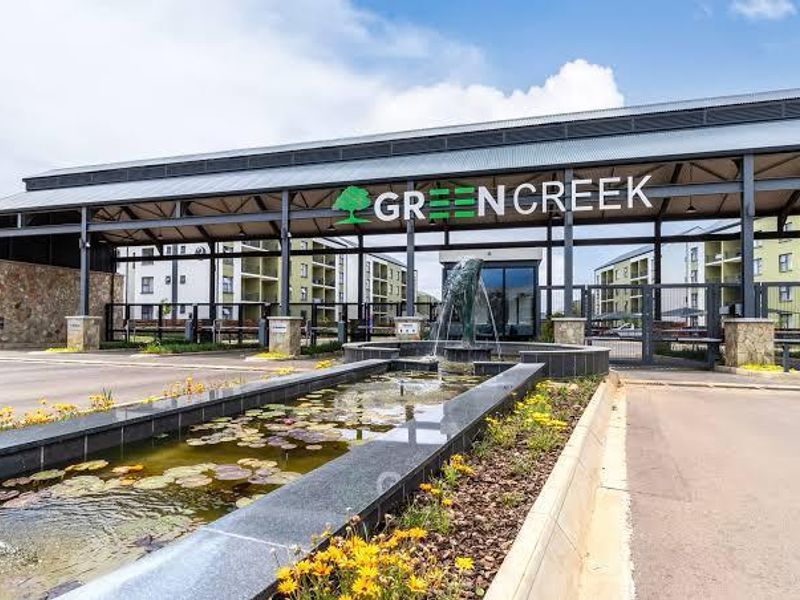 The main entrance to Greencreek apartment complex featuring a modern metal structure, stone accents, and a decorative water feature.