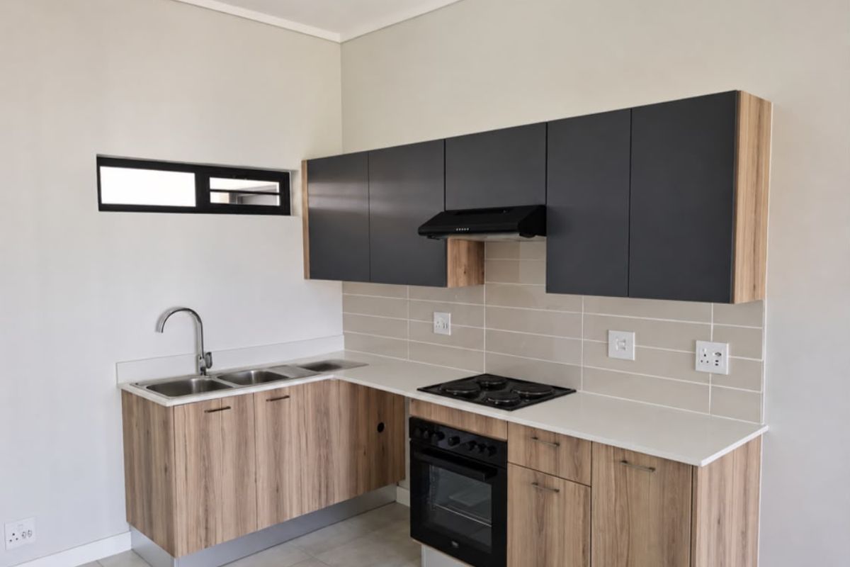 Modern kitchen featuring wood-grain cabinetry, stone countertops, a double sink, and integrated appliances including an oven, hob, and extractor fan.