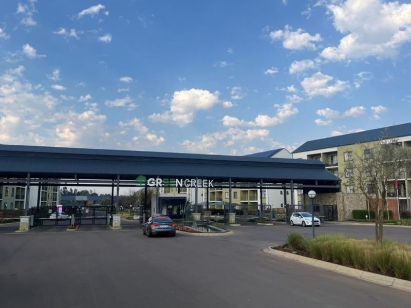 The main entrance and security gatehouse of the Greencreek apartment complex, featuring modern architectural design and paved access roads.