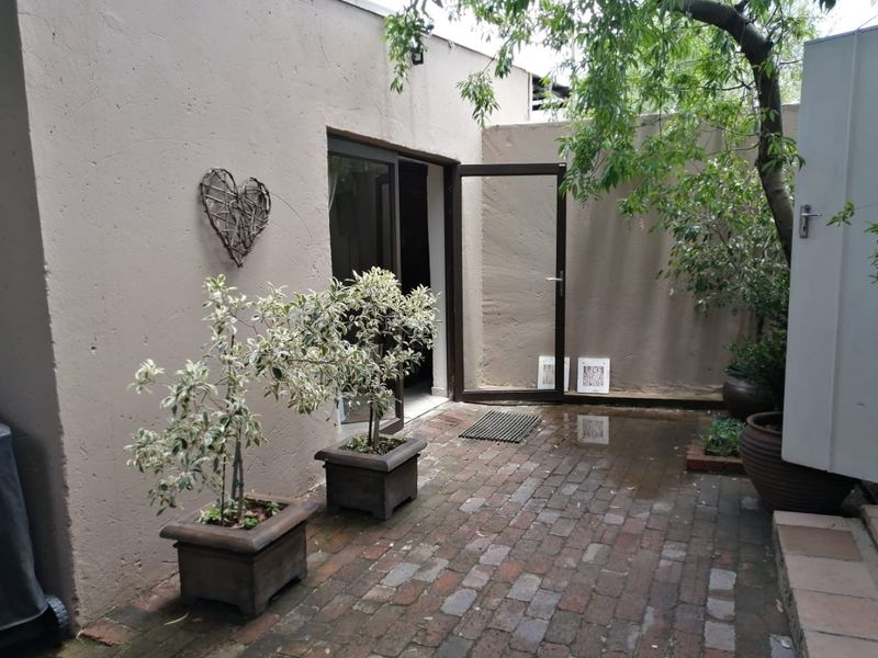 A private paved patio area featuring brick flooring and direct access to the interior through an aluminium framed glass door.