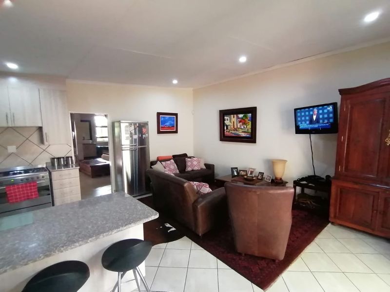 Open-plan living area featuring a functional kitchen with granite countertops, gas stove, and tiled flooring, seamlessly flowing into the lounge space.