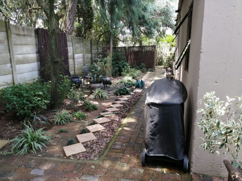 A private rear garden featuring brick paving, stone stepping stones, and a precast concrete boundary wall, providing a quiet outdoor space.