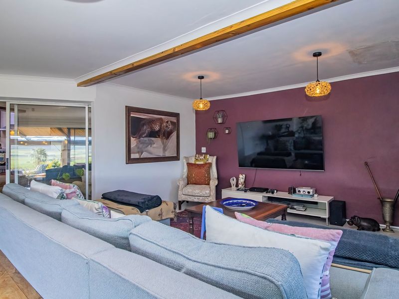 Spacious living room featuring a stone accent wall, exposed timber ceiling beam, and sliding glass doors leading to an outdoor area.